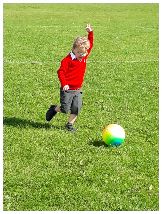 child about to kick football in a field